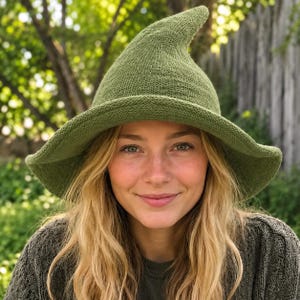 Könnte beinhalten: Ein spitzer, olivgrüner Strickhut mit einer breiten, leicht geschwungenen Krempe. Der Hut besteht aus einem strukturierten, gewebten Stoff mit einer ausgeprägten konischen Krone, die sich nach oben hin zu einer weichen Spitze verjüngt.