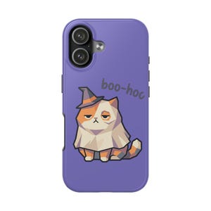 May include: A purple smartphone case featuring a graphic of a calico cat wearing a witch hat and a ghost sheet. The cat has a grumpy expression, and the text "boo-hoc" is printed in dark gray above the cat. The case has a dual camera cutout.