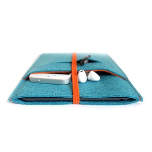 Op de afbeelding: Een teal gevoerde laptophoes met een oranje elastische band sluiting. De hoes heeft een vak voor een telefoon en een ander vak voor koptelefoons of andere kleine items.