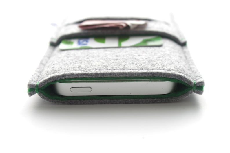 May include: A gray felt phone case with a green trim. The case has a pocket on the front for cards.