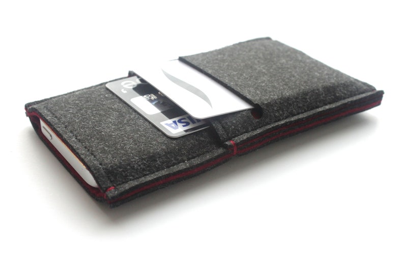 May include: A gray felt phone case with a red stitched edge. A credit card is tucked into the case's pocket.