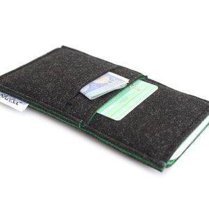 May include: A black felt phone case with green stitching. The case has a pocket for cards and cash. The case has the word "Shilsi" printed on it.