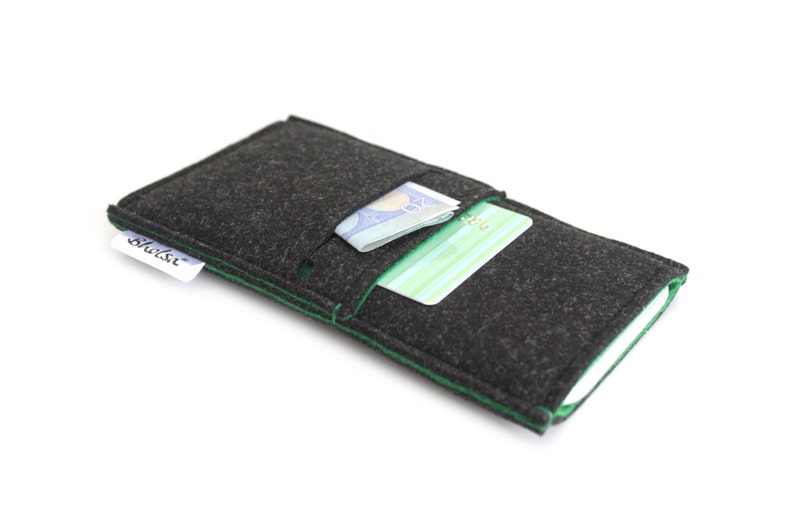 May include: A black felt phone case with green stitching. The case has a pocket for cards and cash. The case has the word "Shilsi" printed on it.