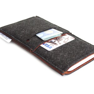 May include: A gray felt phone case with a brown leather trim. The case has a pocket for cash and cards. The case is shown with a credit card and cash inside.