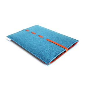 May include: A blue felt laptop sleeve with an orange leather strap and stitching. The sleeve is folded in half and the strap is wrapped around the sleeve.