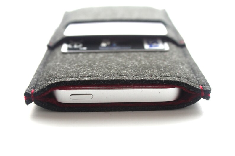 May include: A gray felt phone case with a red stitch detail. The case has a slot for a credit card or ID card.