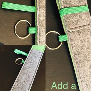 May include: A gray felt case with a bright green interior and elastic band, designed to hold items. A gold-colored keyring is attached. The text "Add a Keyring" is visible in green.