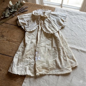 May include: A white ceramic mug with a black handle and the text "But First, Coffee" in a bold, black font. The mug is set against a blurred background, suggesting a cozy setting.