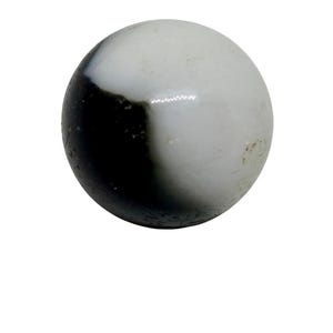 May include: A single, round marble with a striking black and white design. The marble is split diagonally, with one half a solid black and the other half a creamy white. The surface is glossy.