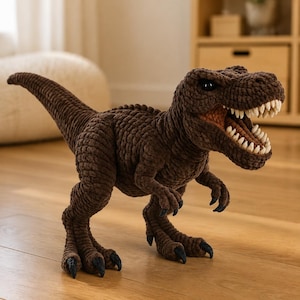 Peut inclure: Un jouet en peluche Tyrannosaurus Rex crocheté en marron avec une surface en fil côtelé texturé. Le dinosaure présente une gueule grande ouverte montrant des dents blanches, des yeux sombres et des griffes noires acérées sur les pattes.