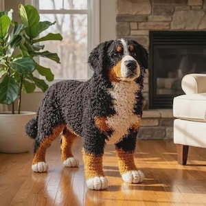 May include: A handcrafted crochet Bernese Mountain Dog figurine featuring a tri-color coat of black, rust, and white yarn. The plush dog stands in a realistic pose with a white blaze on its face, textured fur, and white paws, showcasing detailed stitching.