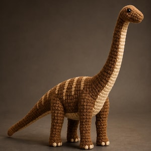 Peut inclure: Un jouet dinosaure au crochet avec un long cou et une longue queue, réalisé en fil marron foncé avec des rayures beige clair sur le dos et le cou. Le dessous et les pieds sont beige clair, et la créature a de petits yeux en perles noires.