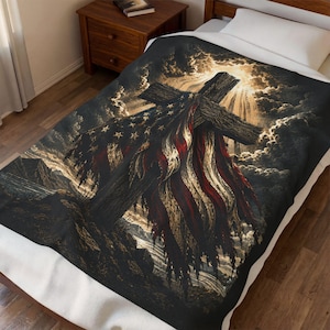 May include: A rectangular blanket featuring a dark, dramatic scene of a wooden cross draped with a tattered American flag. The background displays swirling dark clouds with bright, golden light rays emanating from behind the cross, creating a high-contrast, textured visual effect.