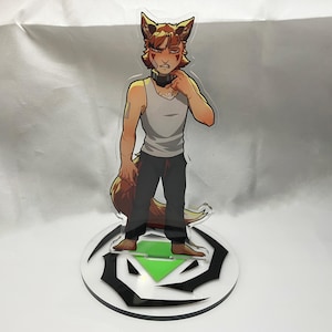 May include: A clear acrylic standee of a cartoon character with fox-like features. The character wears a white vest top, black trousers, and a black choker. The standee is on a round base with a black and green design.