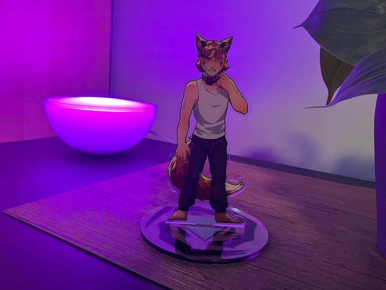 May include: A clear acrylic figure of a fox-like character in a white tank top and black pants, standing on a circular base. The figure has brown fur and ears, with a tail. The background features a purple-lit lamp and a plant.