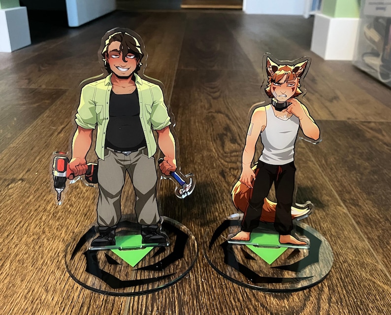May include: Two acrylic standees featuring cartoon characters. One holds a drill and hammer, wearing a green shirt, black shirt, and gray pants. The other is a fox-like character in a white tank top and black pants. Both stand on circular bases.