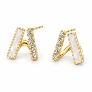 May include: A pair of gold stud earrings featuring a V-shaped design. Each earring consists of two connected bars: one bar is inlaid with a smooth white mother-of-pearl stone, and the other bar is set with five small, clear, round-cut cubic zirconia stones.