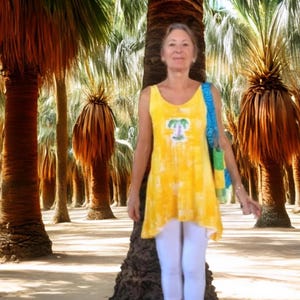 A woman wearing a yellow sleeveless top with a palm tree design