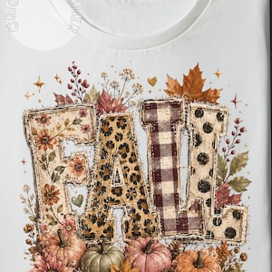 May include: A white t-shirt featuring the word FALL in large, distressed-edge letters. Each letter has a different pattern: floral, leopard print, brown and white buffalo plaid, and black polka dots. The design includes pumpkins, autumn leaves, and berries.