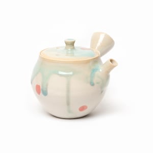 Peut inclure: Une théière kyusu en céramique avec une poignée latérale et un bec court. Le corps est blanc cassé avec un vernis brillant présentant des coulures bleu clair sur les côtés et de petites taches circulaires roses dispersées. Couvercle assorti.