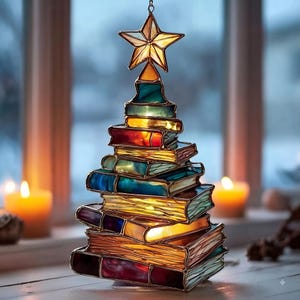May include: A stained glass ornament shaped like a Christmas tree constructed from stacked, multi-colored glass books. The tree is topped with a five-pointed star and features warm, glowing light emanating from within the glass panels.