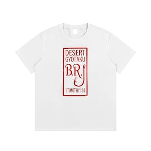 Puede incluir: Una camiseta blanca de manga corta con un gráfico rectangular rojo en el pecho. El gráfico contiene el texto DESERT GYOTAKU, las letras B.R.J con un anzuelo integrado en la J, y el texto 1 TIMOTHY 1:14 en la parte inferior del diseño.