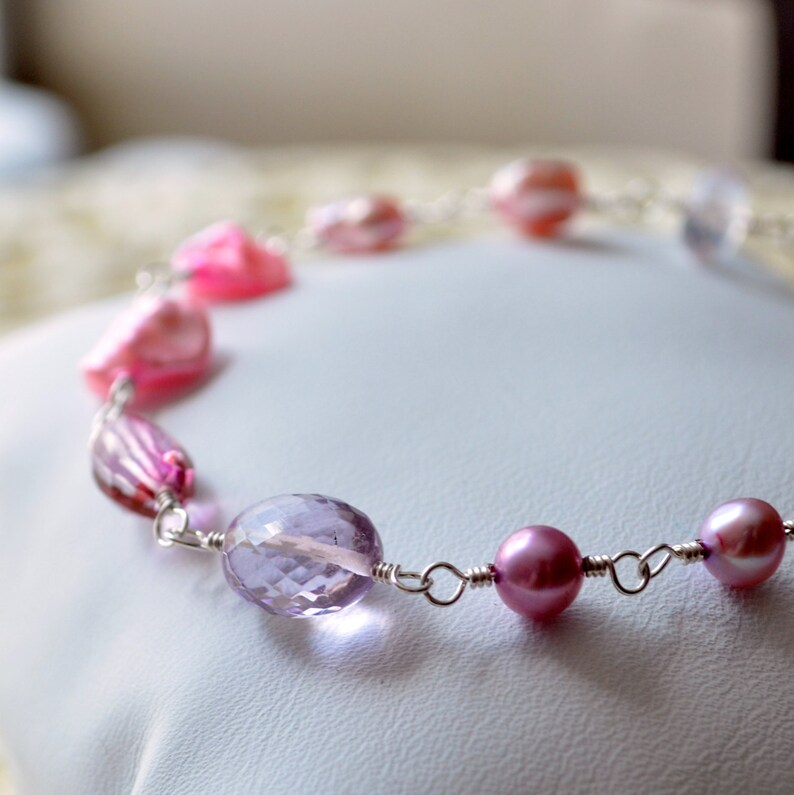 May include: A delicate necklace with pink and purple beads, including amethyst and freshwater pearls, connected by silver wire.