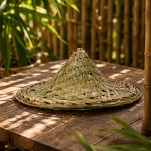 Puede incluir: Un sombrero cónico construido con tiras de bambú tejidas. El sombrero presenta una corona puntiaguda y un ala circular ancha con una paleta de colores verde claro y bronceado natural, mostrando un intrincado patrón entrecruzado.
