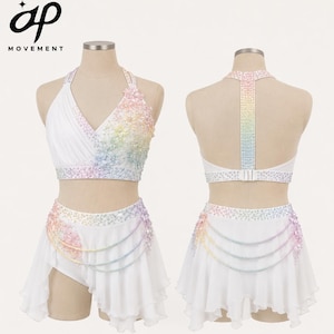 May include: A white two-piece dance costume featuring a halter-style crop top and a skirt with an asymmetrical hem. The set is embellished with iridescent, rainbow-colored crystals and floral appliqués, with delicate beaded chains on the skirt.