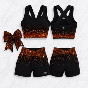 Könnte beinhalten: Ein schwarzes Sportset bestehend aus einem Sport-BH und einer Shorts mit überkreuztem Rücken sowie einer passenden Haarschleife. Die Kleidungsstücke sind mit einem orangefarbenen Strass-Verlaufsmuster und den Buchstaben ap in kleiner silberner Schrift verziert.