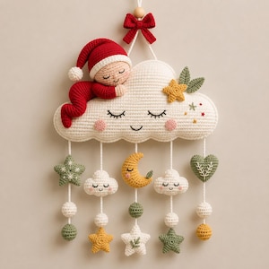 Puede incluir: Un colgante de pared de ganchillo con una figura dormida con traje y gorro rojos sobre una gran nube color crema. Debajo, cinco cordones blancos suspenden varias formas de ganchillo, incluyendo estrellas, nubes pequeñas, una luna creciente amarilla y un corazón verde.