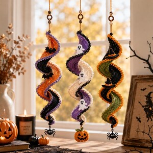 May include: Three hanging spiral decorations made of crocheted yarn. The first is orange and black with small black bats. The second is purple and white with small white ghosts and a pumpkin charm. The third is green and black with witch hats.