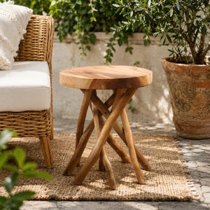 May include: A round side table featuring a smooth, light brown wooden top and a base constructed from multiple interlocking, branch-like wooden legs. The natural wood grain is visible on the circular surface, and the legs are arranged in a crisscross pattern to provide support for the tabletop.