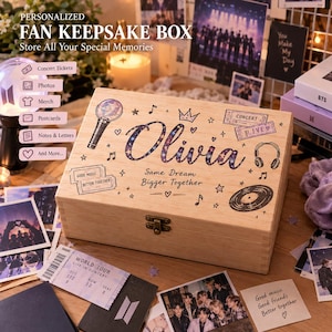 May include: A rectangular wooden keepsake box featuring the name Olivia in a galaxy-patterned font, surrounded by illustrations of a light stick, headphones, a vinyl record, concert tickets, stars, and musical notes, with the text Same Dream Bigger Together.