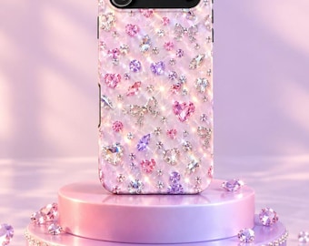 May include: A smartphone case featuring a light pink background adorned with scattered sparkling crystals, rhinestones, and small silver bow accents. The case has a black camera module cutout at the top and a glossy, reflective finish throughout.