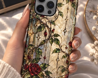 May include: A smartphone case featuring a stained glass design with intricate gold filigree, green climbing vines, and deep red roses. The background has a textured, pearlescent cream finish with vertical lines and small star-shaped accents.