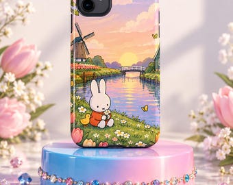 May include: A phone case featuring a colorful illustration of a white rabbit sitting in a grassy field with a windmill, a river, and a sunset sky. The design includes small yellow ducks, flowers, and butterflies in a soft, pastel-toned landscape.