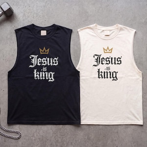 May include: Two sleeveless shirts, one black and one off-white, each featuring a gold crown graphic above the text "Jesus is king" in a black or white gothic-style font. The shirts have a crew neckline and are displayed on a grey surface.
