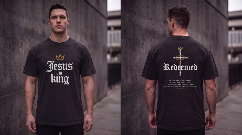 Op de afbeelding: Een zwart t-shirt met korte mouwen, voorzien van een gouden kroon en de witte tekst "Jesus is king" op de voorzijde. De achterkant toont een kruis met een doornenkroon, het woord "Redeemed" en een bijbelvers in witte tekst.