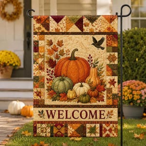 May include: A rectangular garden flag featuring a patchwork border of autumn-colored triangles and squares. The center displays a collection of pumpkins and gourds in orange, green, and white, surrounded by fall leaves and a black bird. The word WELCOME is printed at the bottom.