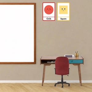 Puede incluir: Un escritorio de madera con un cajón color verde azulado y una silla de oficina de color rojo oscuro. Sobre el escritorio hay dos adhesivos de pared rectangulares: uno con un círculo rojo y el texto Circle, y otro con un cuadrado amarillo y el texto Square.