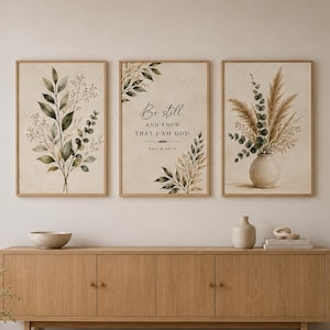 Puede incluir: Un conjunto de tres cuadros de pared con ilustraciones botánicas y el texto Be still and know that I am God Psalm 46:10. Las láminas muestran hojas verdes, hierbas secas y un jarrón sobre un fondo de color beige claro.