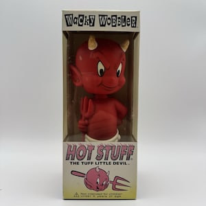 May include: A red Hot Stuff the Tuff Little Devil bobblehead figure inside a rectangular cardboard box. The box features the text Wacky Wobbler at the top and Hot Stuff The Tuff Little Devil at the bottom, with a small illustration of the character.
