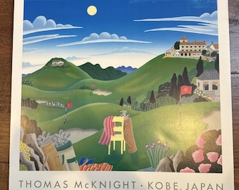 May include: A square art print by Thomas McKnight titled Kobe, Japan, depicting a stylized golf course with rolling green hills, a yellow chair, golf bags, red flags numbered 3 and 4, a large white building on a hill, and a bright yellow moon.