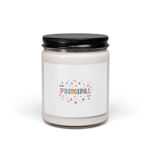 May include: A clear glass candle jar with a black metal lid containing white wax. The front label features the word PRINCIPAL in multicoloured, patterned block letters, surrounded by a scattering of small, colourful stars in various shades.