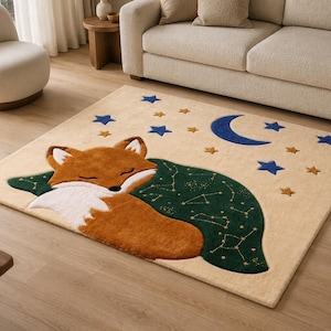 May include: A rectangular area rug with a beige background featuring a sleeping orange and white fox curled up under a dark green blanket decorated with gold constellation patterns, surrounded by blue and gold stars and a blue crescent moon.