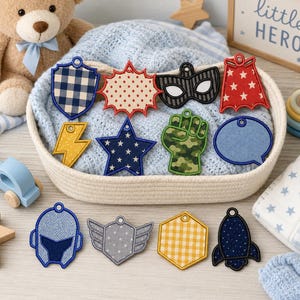 May include: A collection of fabric patches featuring various shapes and patterns, including a blue gingham shield, a red star-patterned cape, a black mask, a yellow lightning bolt, a blue star, a green camouflage fist, and a blue speech bubble.