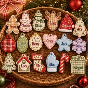 May include: A collection of embroidered fabric Christmas ornaments in various shapes including gingerbread people, snowmen, reindeer, hats, bells, stars, hearts, snowflakes, trees, houses, stockings, mittens, candy canes, and gift boxes with names.