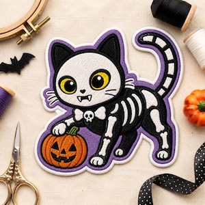 May include: An embroidered patch featuring a black and white cat with large yellow eyes, wearing a white bow tie with a skull icon. The cat has a skeleton pattern on its body and is holding an orange jack-o'-lantern pumpkin with a purple border.