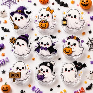 May include: A set of nine clear acrylic ghost-shaped charms featuring various Halloween designs, including a ghost with a witch hat, a ghost holding a pumpkin, a ghost with a lantern, a ghost with a lollipop, a vampire ghost, a ghost with a flower crown, a ghost with a BOO sign, a ghost with a mug, and a ghost with a bat balloon.